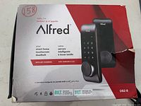 Front of retail box showing Alfred DB2-B branding and black finish deadbolt image
