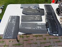 Five keyboards laid on table showing layouts, colors, and condition