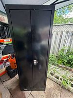 Full front view of black steel two-door storage cabinet with combination lock