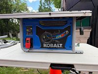 Side view of Kobalt table saw showing brand logo, power switch and adjustment wheel