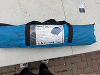 Tent packed in blue carry bag with label showing model and features