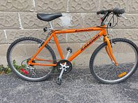 Full side view of orange Raleigh Kilimanjaro mountain bike against wall