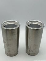 Front view of two stainless steel tumblers with lids