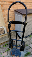 front view of black steel hand truck with blue toe plate and pneumatic wheels