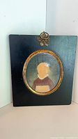 Front view showing miniature portrait, gilt surround, black backing, hanger