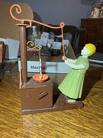 front view of painted metal wind-up toy with woman pumping water