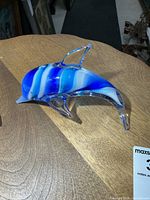 Left side view of blue and white art glass dolphin figurine on wood surface