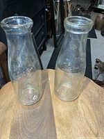 Two embossed glass milk bottles on table