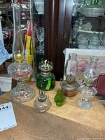 Group of five mini oil lamps and spare green chimney on table