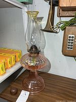 Full view of pink glass oil lamp on table