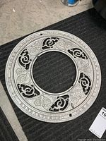 Full view of round cast iron grate showing floral design and central opening