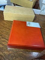 Closed tan cardboard box and closed red wooden jewelry box