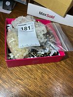 Box showing assorted jewelry pieces and MaxSold lot tag