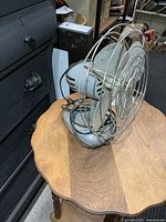 Side view of gray metal fan on small table