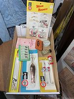 Tray showing all packaged lures, tins, bottle and booklet
