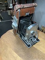Camera front three-quarter view showing bellows extended and leather panels