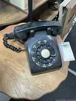 Front view of black rotary dial phone showing dial and handset