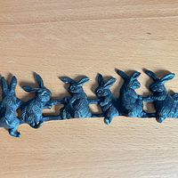 Full view of cast iron rabbit hook rack on wood surface