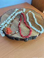 Four beaded necklaces displayed on wood slice board
