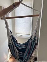 Full view of hammock chair hanging from wood spreader bar, showing suspension ropes and striped fabric