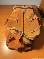 Top view of duffel showing suede surface, top zipper, end pockets, handles and detachable strap