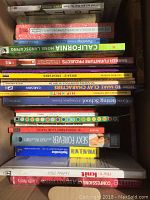 Photo showing a box packed with assorted books stacked horizontally and vertically, titles include crocheting, growing, furniture projects, nutrition and cooking.