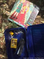 Photo of office scissors, stapler, push pins, and playing cards with evening gown sketchbook on grass outdoors