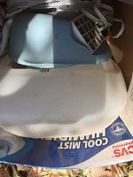 Top view of a commode chair showing the white plastic seat with grey armrests and metal frame, one unused with owner bags underneath