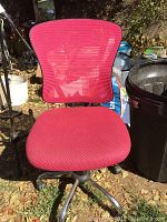 Front view of pink mesh office chair showing cushioned seat and mesh backrest in outdoor setting.
