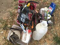 Overview of gardening tools, sprayers, chemicals arranged on ground showing different items included in lot.