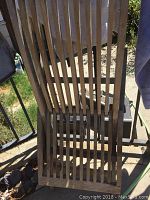 Top-down view of a broken teak bench with slatted construction and weathered finish.