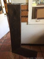 Photo of the L shaped wooden corner shelf in a standing position showing dark wood finish and dimensions relative to door and floor tiles.