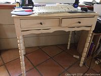 Front view of solid wood white desk with two drawers, showing turned legs and scalloped front apron.
