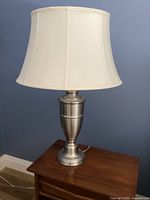 Full view of lamp on table: metal base, white shade, power cord
