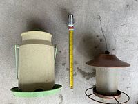Beige plastic feeder and copper-tone cylinder feeder beside tape for scale