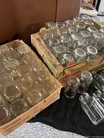 Two boxes filled with assorted clear glass jars