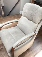 Front angled view of beige upholstered oak arm recliner chair