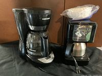 Both coffee makers side by side with bag of filters