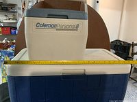Large blue Coleman chest cooler with white lid, small Personal 8 cooler on top, width measured with tape