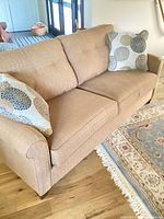 Full view of tan La-Z-Boy couch with two accent pillows