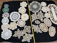 All doilies laid out on black cloth with tape measure for scale
