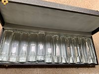 open case showing all twelve glass knife rests lined up