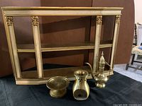 Curio shelf cabinet with three brass items in front