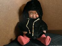 Front view of doll seated showing outfit and face