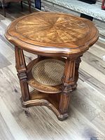 full view of table showing round top, legs and lower cane shelf