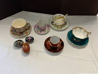 Overview of five teacup sets and three eggs on table