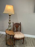 Lamp standing on demilune table beside carved chair