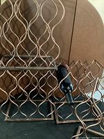 Two copper-tone metal wine racks showing wavy lattice sides and bottle placement