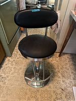 Front view of black faux leather bar stool with chrome base