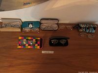Overview of six pairs of eyeglasses with their cases arranged on tabletop